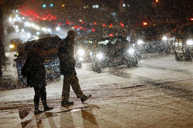 华盛顿街头过马路的行人。美国国家气象局警告说，降雪和飞雪会严重影响到民众生命财产安全。很多超市也排起了长长的队伍，不少民众也前往加油站，趁着大雪来临之前“喂饱”爱车。（中新网/图）