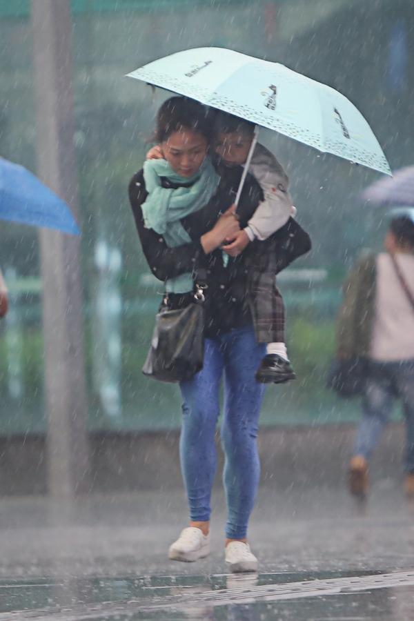 12日傍晚深圳大暴雨，罗湖街头一位家长背着孩子前行。南方日报记者 朱洪波 摄