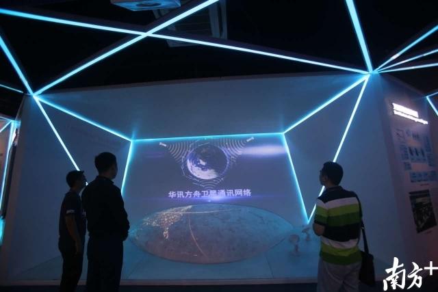 华讯方舟体验中心，前来参观交流的企业人员站在屏幕前了解卫星通讯网络的展示。
