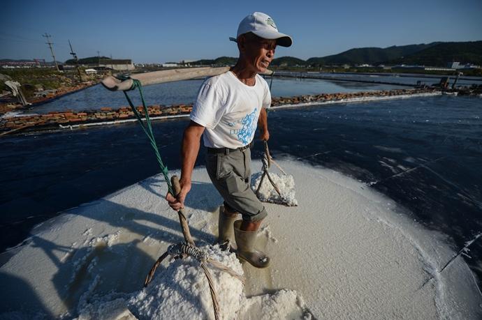 浙江省岱山县盐民沈位明把晒好的盐挑起来，一副担子往往有150多斤重。 对于浙江省岱山县晒盐人来说，夏季阳光最猛烈的7月、8月、9月这三个月是他们劳作的黄金季节。 新华社