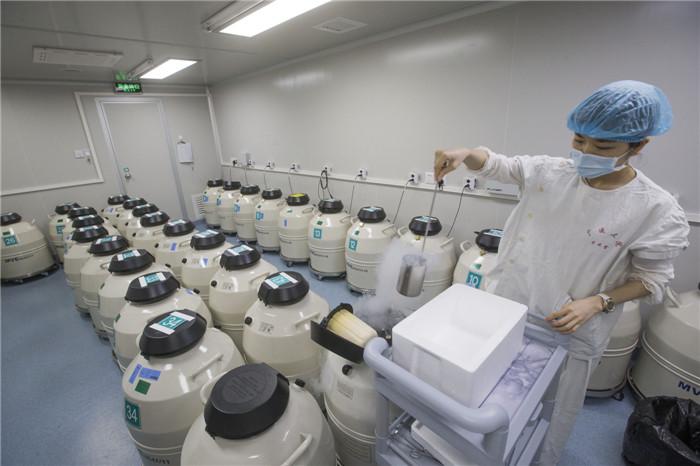 ▲广州医科大学第三附属医院辅助生殖技术实验室里的冷冻仓存放室，医生在冷冻储存容器里舀出低温液氮。