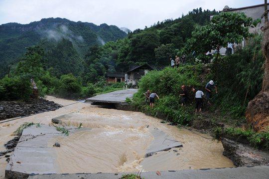 7月4日，铜仁市碧江区坝黄镇太坪村公路被冲毁，村民在旁边挖路通行。新华社发