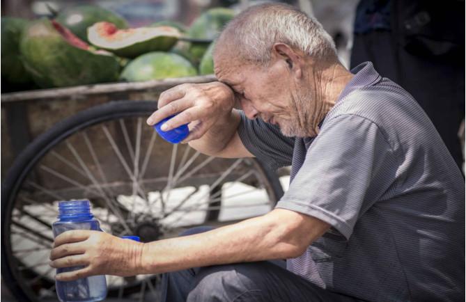 天气炎热，老人仍坚持在街边支起瓜摊