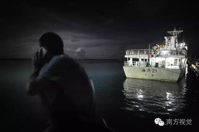 △夜晚，一名永业村村民坐在海边打电话。