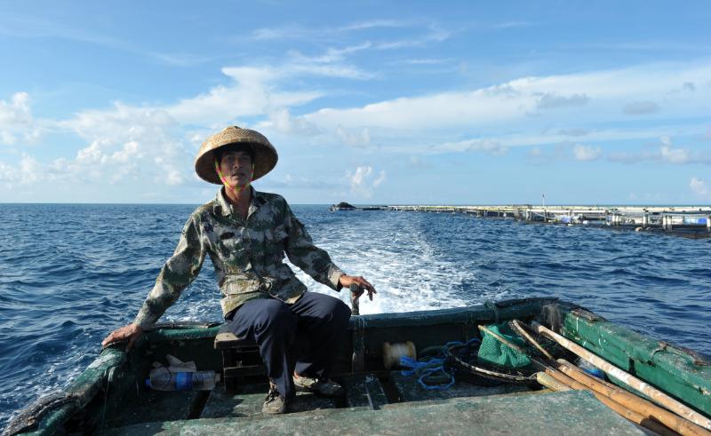 17日，在南沙美济礁礁盘附近，渔民施任平驾驶渔船前往深海养殖基地。新华社发