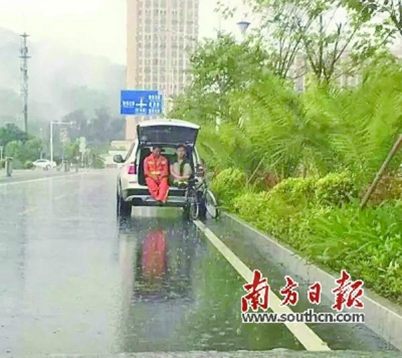 民警张新宇与环卫工人坐在后备箱中避雨。网络截图