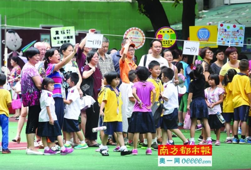 9月5日中午，广州市铁一小学，举着牌子的托管机构工作人员和家长一起接孩子放学。南都记者 冯宙锋 摄