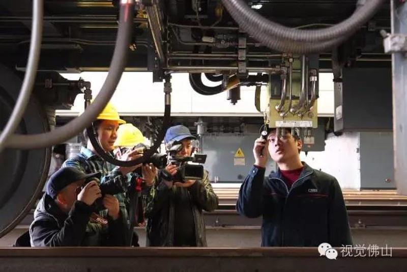 ↑参与体验的人们纷纷举起相机拍摄正在检修列车转向架的广佛线夏南车辆段的工作人员。