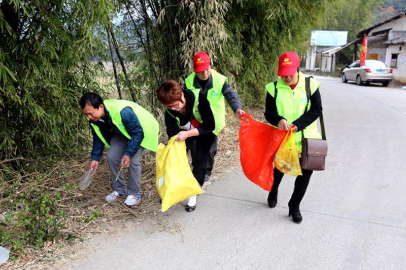 图为志愿者拾掇路人遗落的垃圾。 梁伟 摄