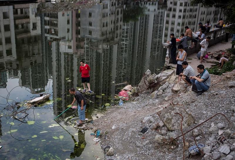 冼村的中心有一个大水塘，成为村里住客常聚的地方。2013年5月，一群人在池塘边钓鱼或捕鱼。