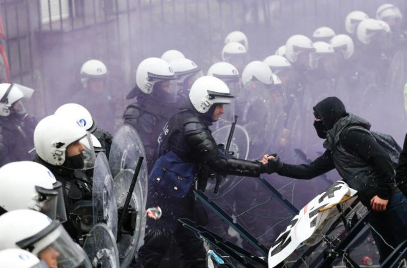 ↑ 11月15日，在比利时首都布鲁塞尔，一名示威者在对峙中与防暴警察握手。当日，比利时军人举行示威游行，抗议军人养老金方案改革，并与警察发生冲突。 新华社记者叶平凡摄