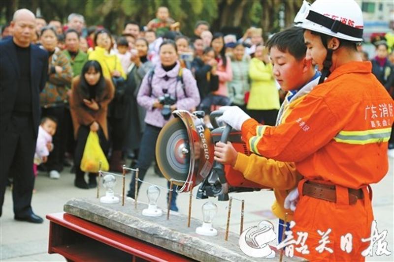 消防官兵指导中学生体验液压切割机的操作。