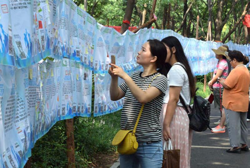 8月9日，一名市民在济南千佛山公园举行的“七月七相亲大会”上用手机记录相亲信息