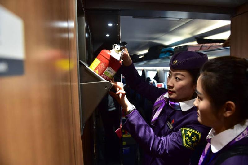 1月12日，陶思嘉（左）在北京南开往合肥南的G29列车上和实习乘务员检查消防器材。