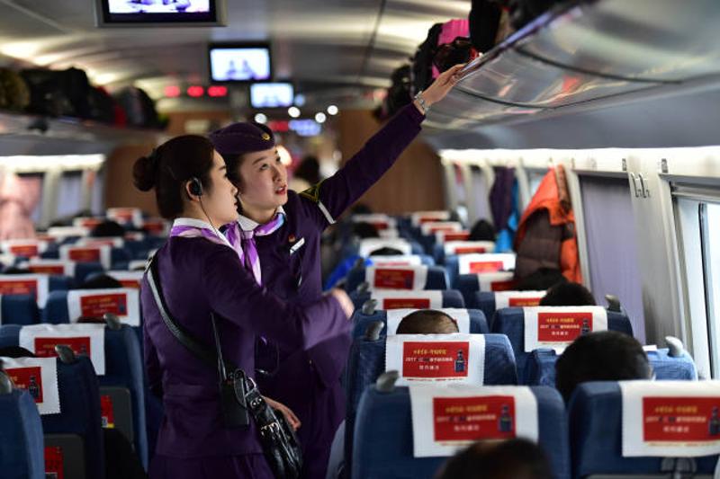 1月12日，陶思嘉（右）在北京南开往合肥南的G29列车上整理行李架。