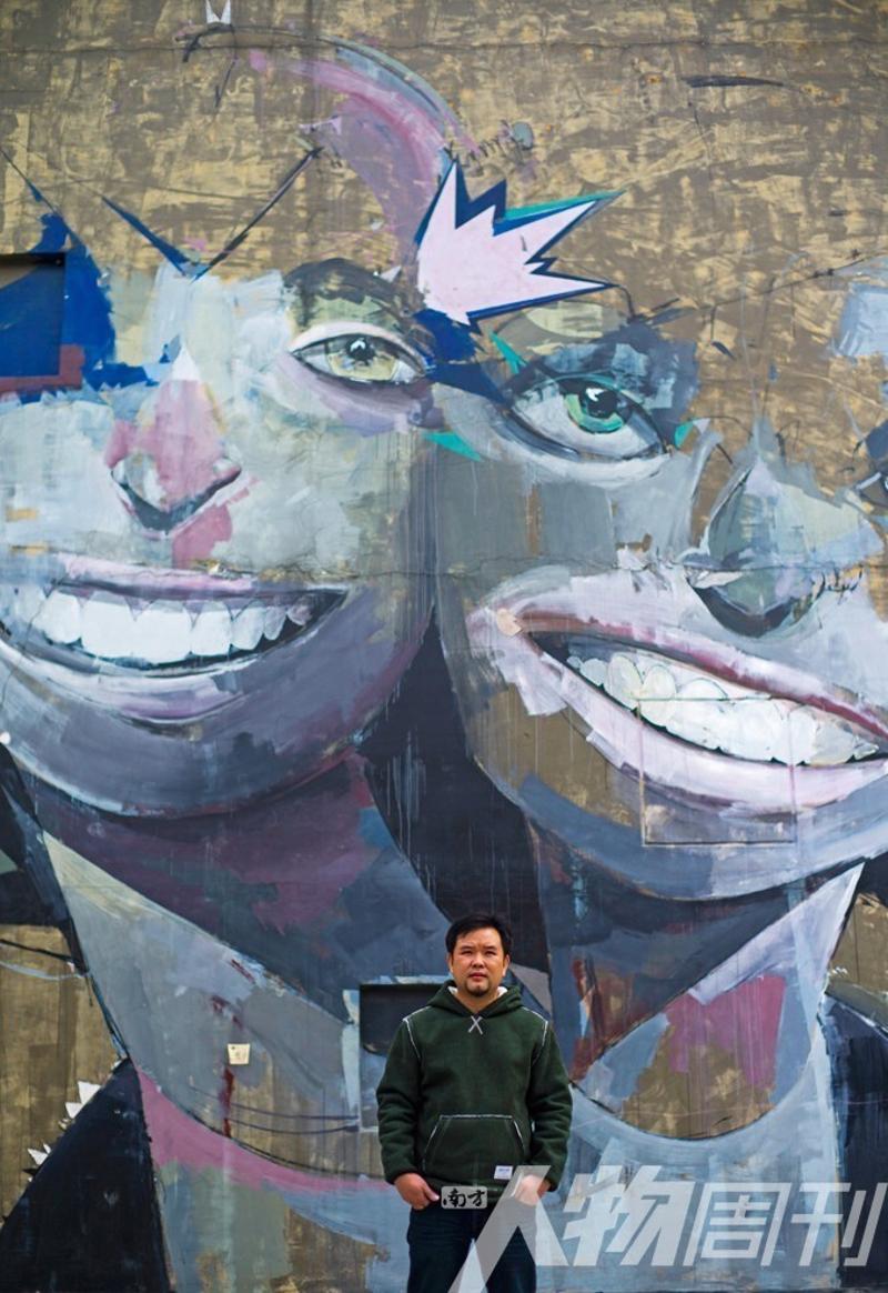 杨福徐站在大芬村街头不知名作者的涂鸦前。最惨的时候，他一年只有三四万的收入，现在他的原创作品已经被人接受，走出了困境图/本刊记者 大食