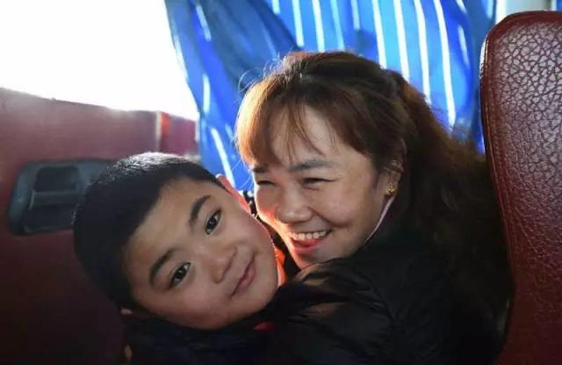 1月22日，在从广州白云机场回市区的大巴上，欧阳生英（右）开心地抱着孩子。新华社记者 薛玉斌摄