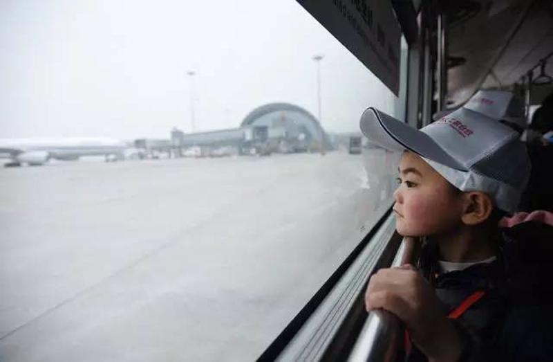 1月22日，在成都双流国际机场，留守儿童王文轩在摆渡车上看飞机，这是他第一次坐飞机。新华社记者 薛玉斌 摄