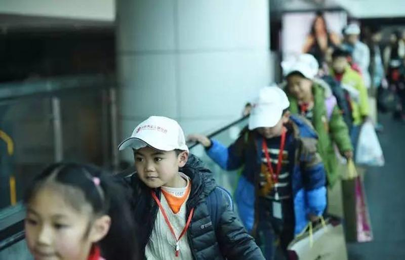 1月22日，留守儿童王文轩（左二）抵达广州后，准备离开广州白云机场。新华社记者 薛玉斌 摄