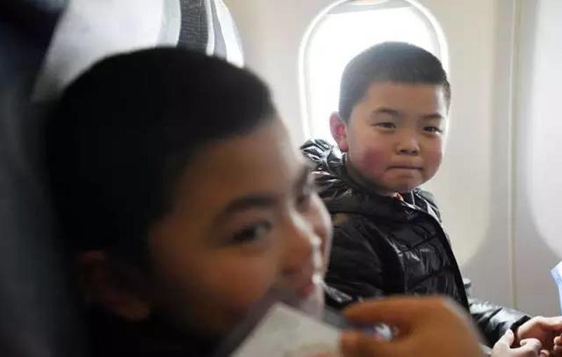 1月22日，留守儿童王宏（右）在成都飞广州的飞机上。新华社记者 薛玉斌 摄