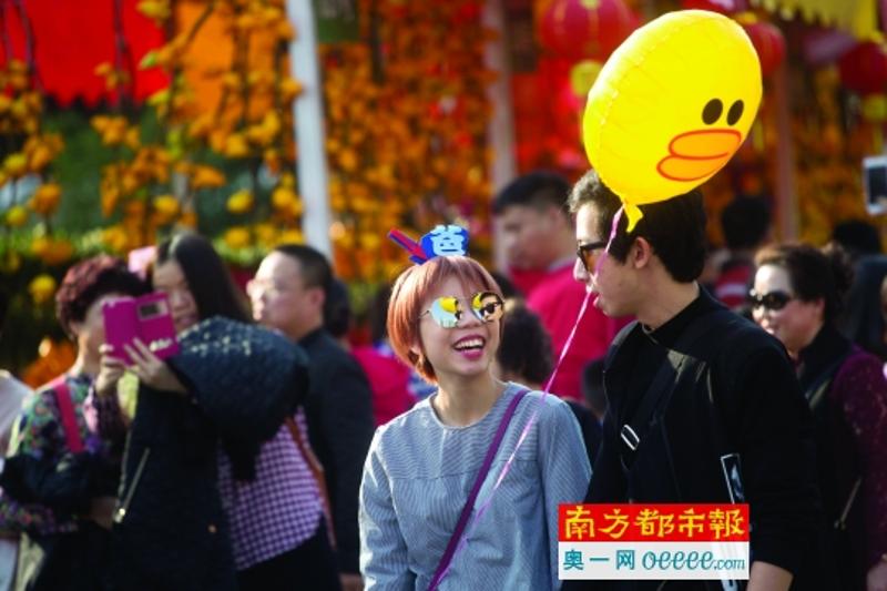 1月25日，天河迎春花市，市民拿着鸡年主题的气球戴着搞怪头饰逛花市。南都记者谭庆驹 摄