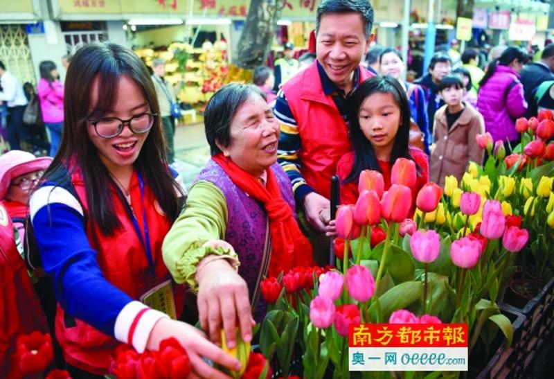 1月25日，西湖路迎春花市，志愿者引导视障人士梁姨（左二）用触摸的方式感受郁金香。新华社 发