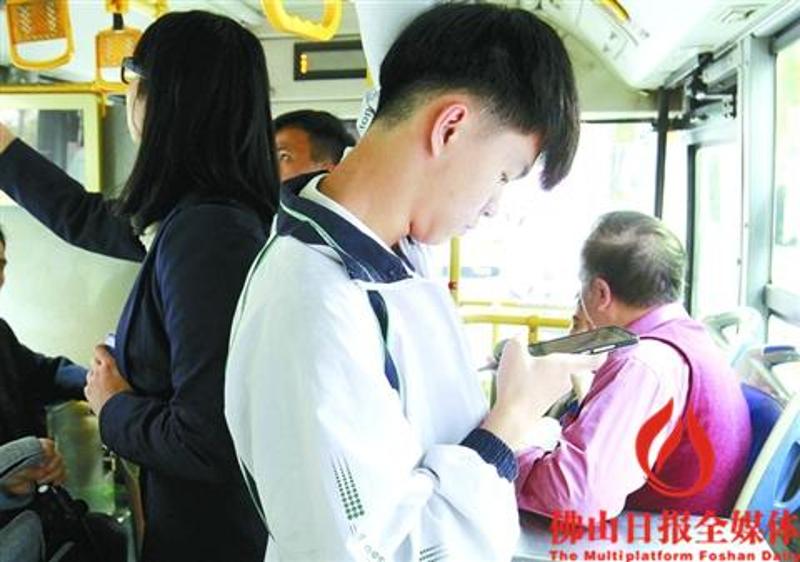 昨日，禅城126路公交车上，一名年轻乘客在用手机上网。 　　/佛山日报记者甘建华摄