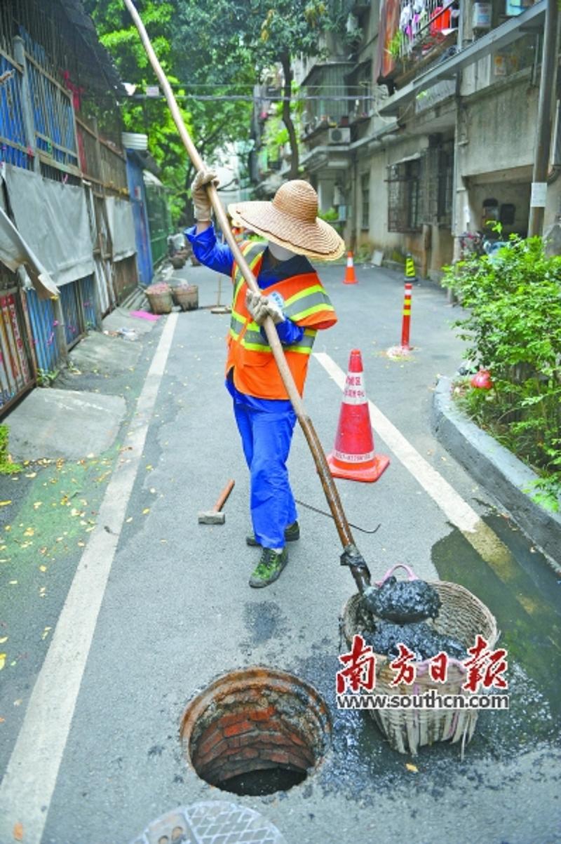 清梳班的女工对小区下水道的淤泥进行清理。