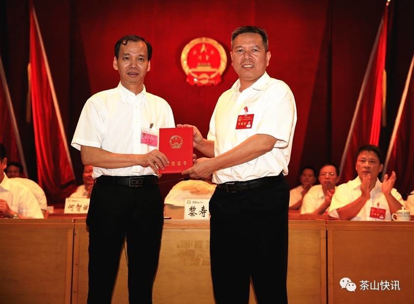 镇委书记黎寿康(右)为新当选的 镇人民政府镇长黄锦发(左)颁发当选