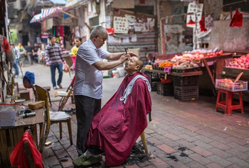 路边理发店的师傅正在给客人刮胡子